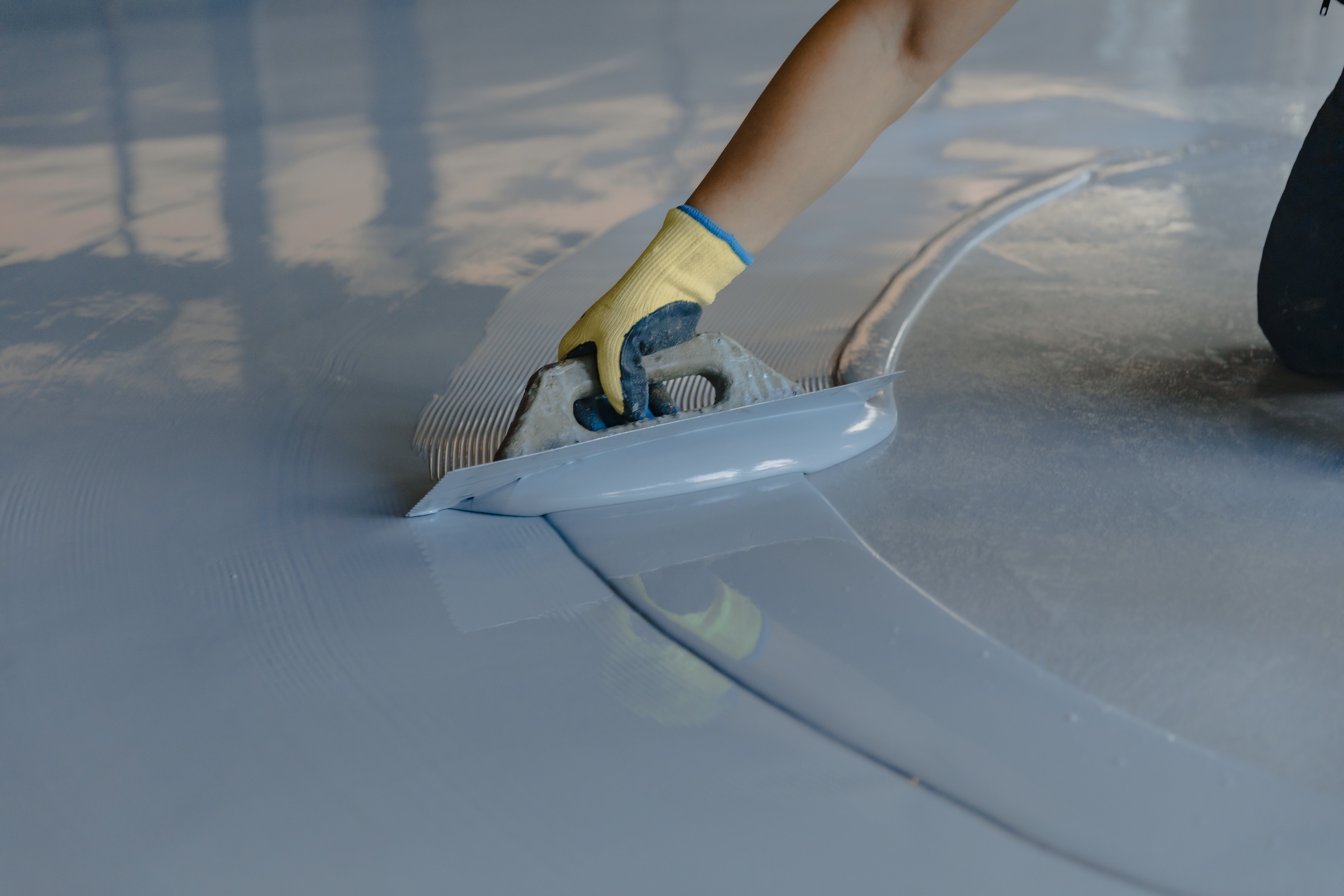worker applies gray epoxy resin new floor